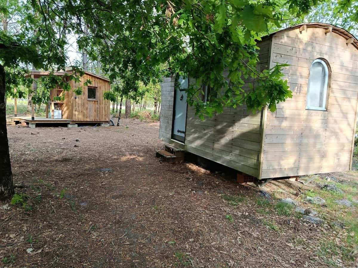 La roulotte en bois et la cabane attenante, sous les chênes de la propriété